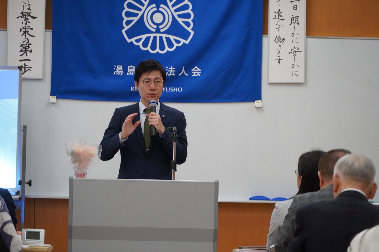 湯島倫理法人会の会旗を背に語りかける石本研氏