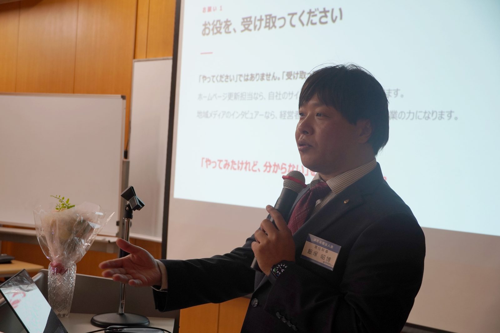 「お役を、受け取ってください」と会員に呼びかける飯塚昭博氏