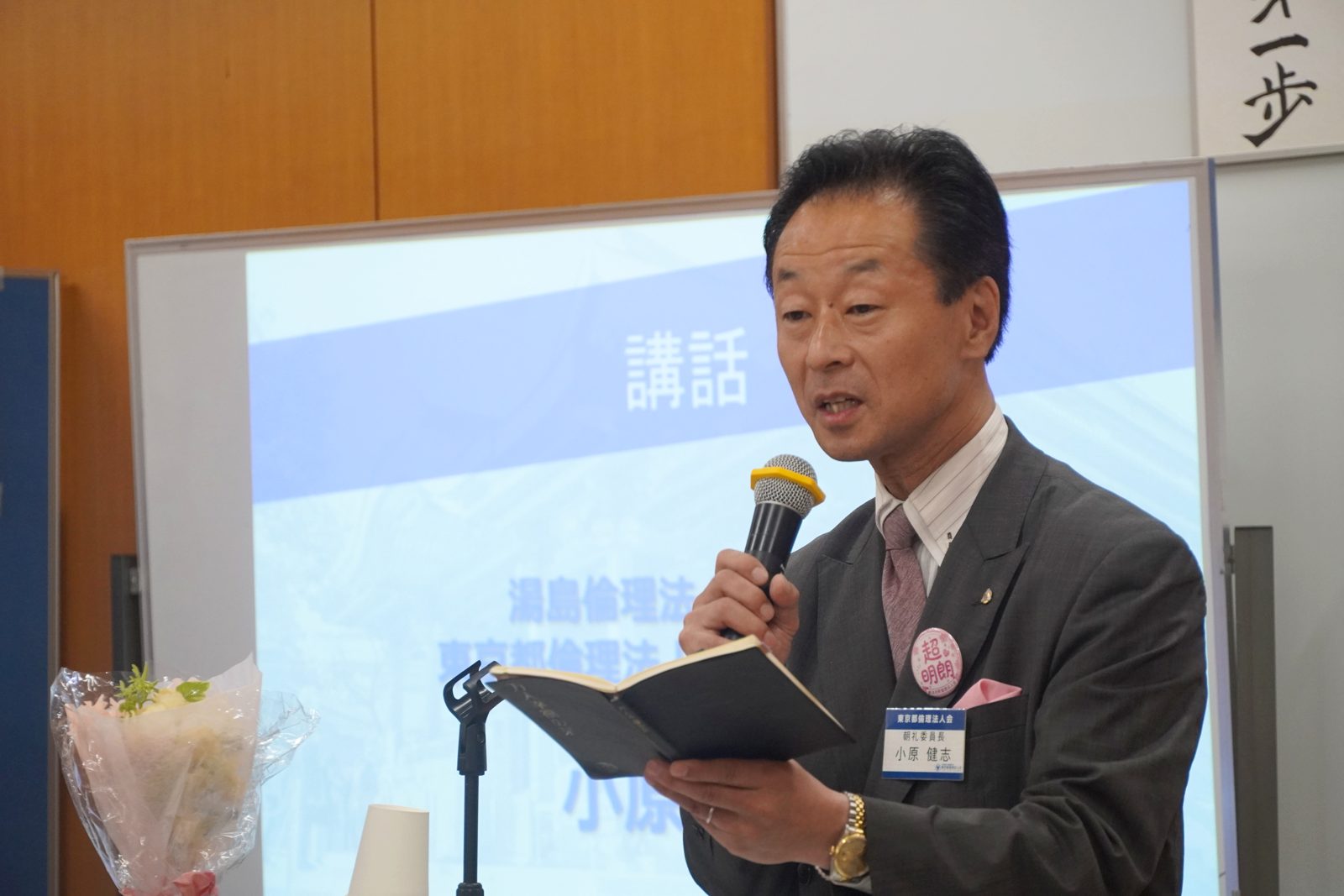 『万人幸福の栞』を手に、ガンジーの一節を紹介する小原健志氏