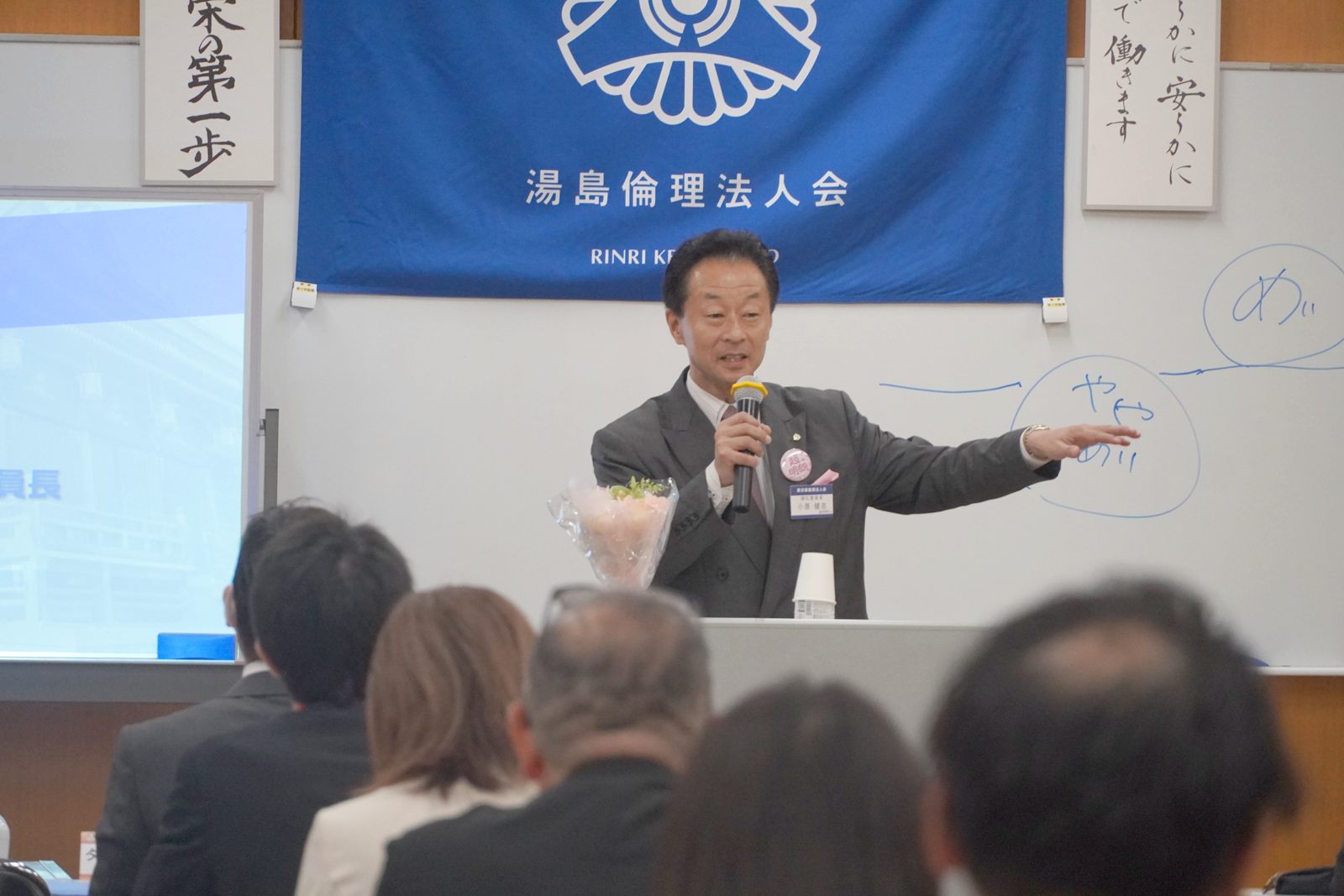 ホワイトボードに「やや明朗」「明朗」「超明朗」を描いて説明する小原健志氏